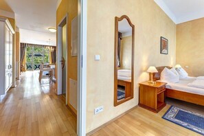 Ein Hotelzimmer mit Bett, Nachttisch, Spiegel und Blick ins Freie.