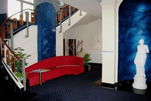 Un intérieur moderne avec un canapé rouge, un escalier et une statue.