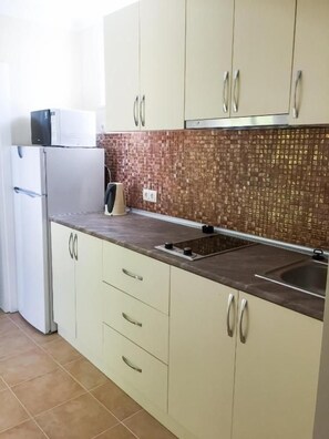 A kitchen with beige cabinets, a tiled backsplash, and a stainless steel sink.