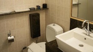 A bathroom with a toilet, sink, and a window above the toilet. - Sofia Residence Apart Hotel (Çamyuva)