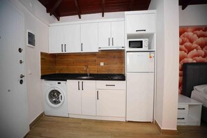 A compact kitchen with a washing machine, microwave, and refrigerator. - Sofia Residence Apart Hotel (Çamyuva)