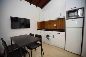 A compact kitchen with a washing machine, a microwave, and a flat-screen TV.