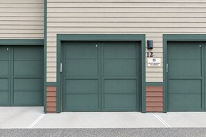 A building with three green double garage doors, a 'PRIVATE RESIDENCE NO PARKING' sign, and the number '12' on the right door.
