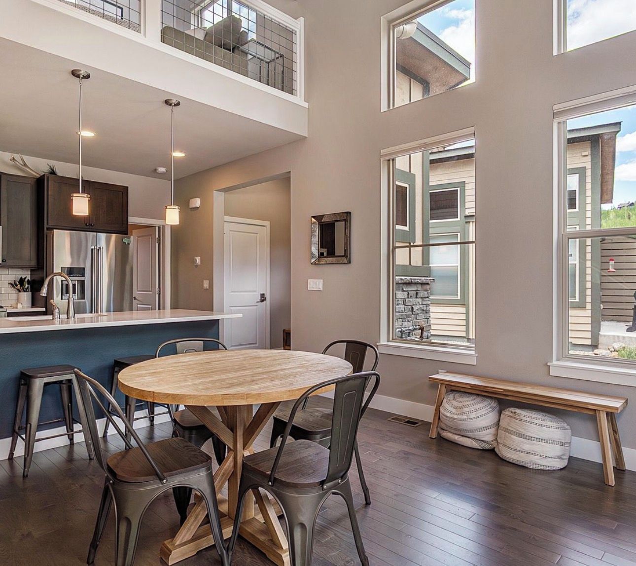 Una cocina moderna con una isla central, taburetes de bar y una mesa de comedor.