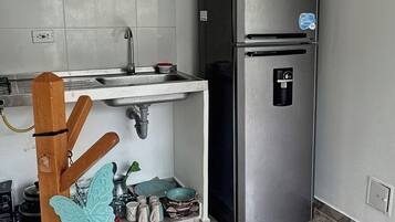 Uma cozinha com geladeira de aço inoxidável, um suporte de madeira suspenso e piso de mármore.