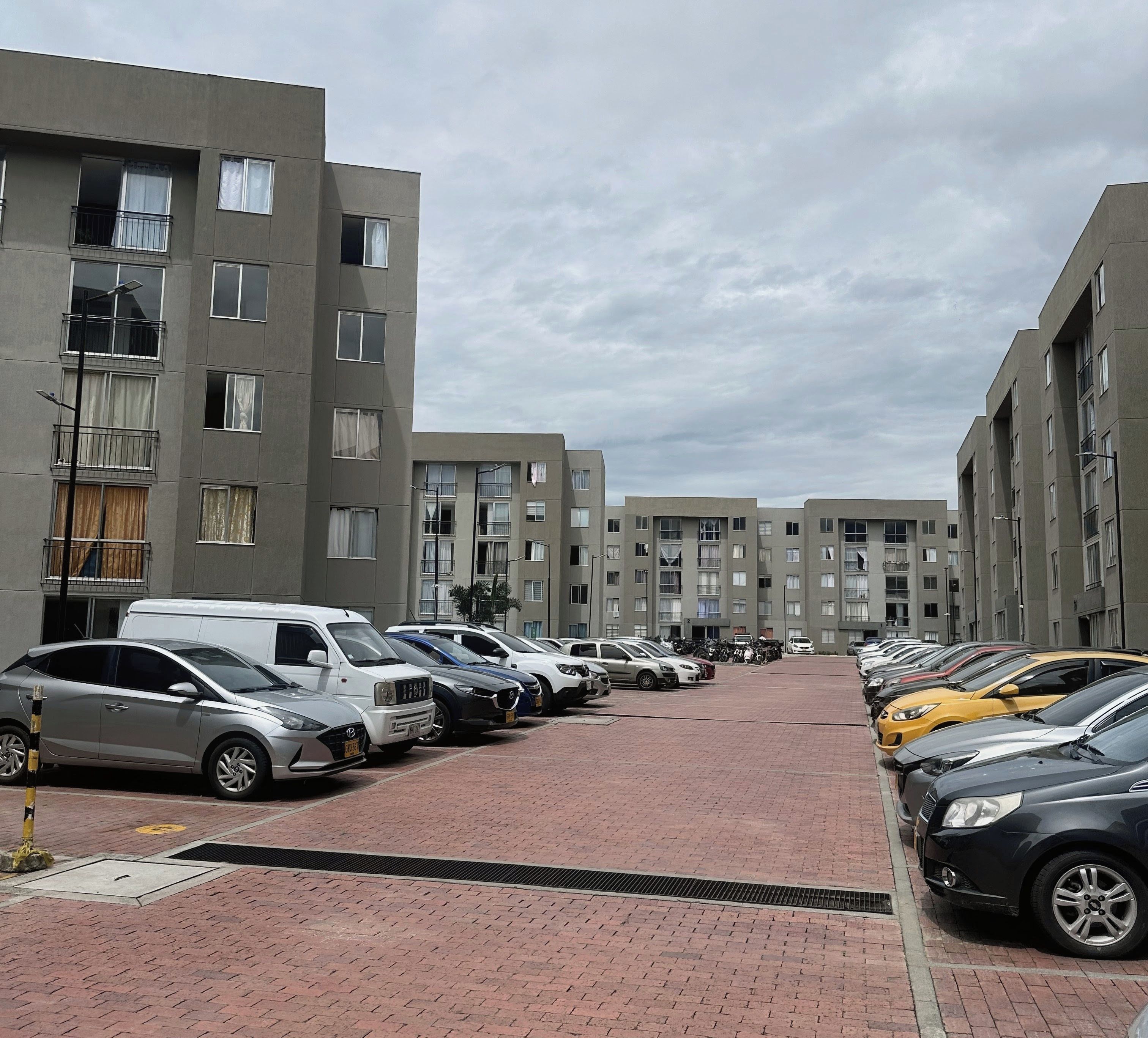 A parking lot with multiple cars and a row of modern apartment buildings.