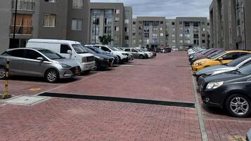 A parking lot with multiple cars and a building with balconies in the background.