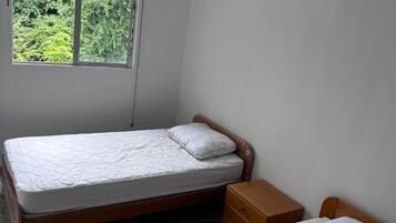 Una cama individual con cabecera de madera y una mesita de noche con cajón.
