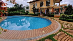 Un hotel moderno con piscina, circondato da giardini curati e un edificio a più piani con balconi.