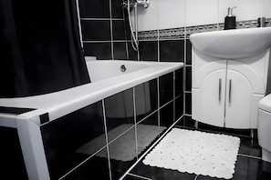 Un baño moderno con bañera, lavamanos e inodoro.