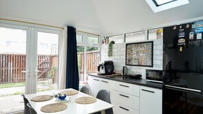 A modern kitchen with a dining area, large windows, and a view of the backyard. - Comfortable 2BDR 2BA Home with Garden in New Cross (Greater London)