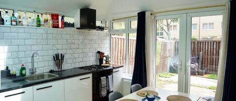 Une cuisine moderne avec des meubles blancs, une cuisinière à gaz et un coin repas avec une table dressée pour deux personnes.