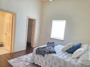 Ein Schlafzimmer mit Bett, Fenster, Tür und Flur.