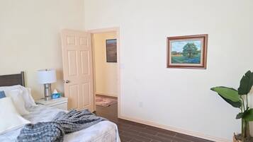 A hotel room with a bed, bedside lamp, and a painting on the wall.