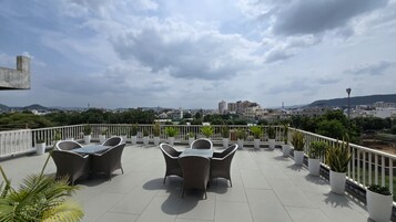 Una terraza en la azotea con mobiliario exterior y plantas en macetas.