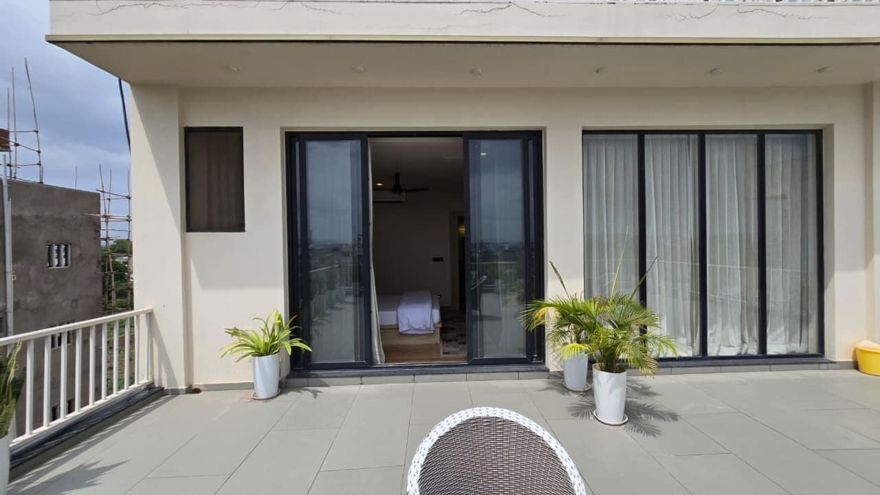 A modern building with a balcony, large sliding glass doors, and potted plants.