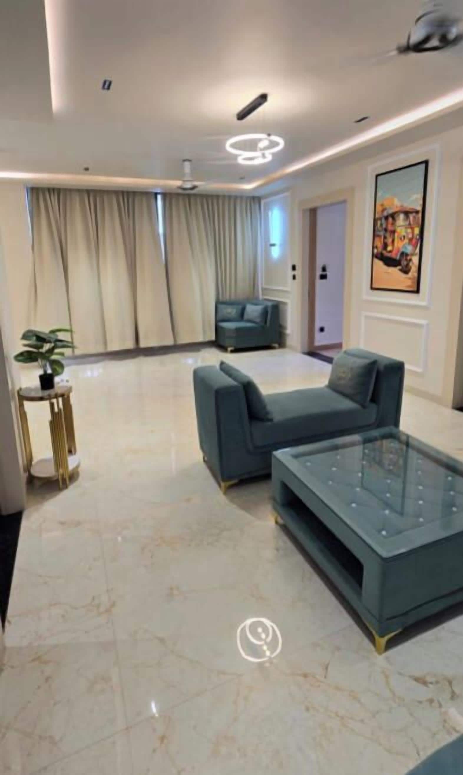 Una sala de estar moderna con un sofá y una mesa de centro de vidrio, una mesita auxiliar y un cuadro en la pared.