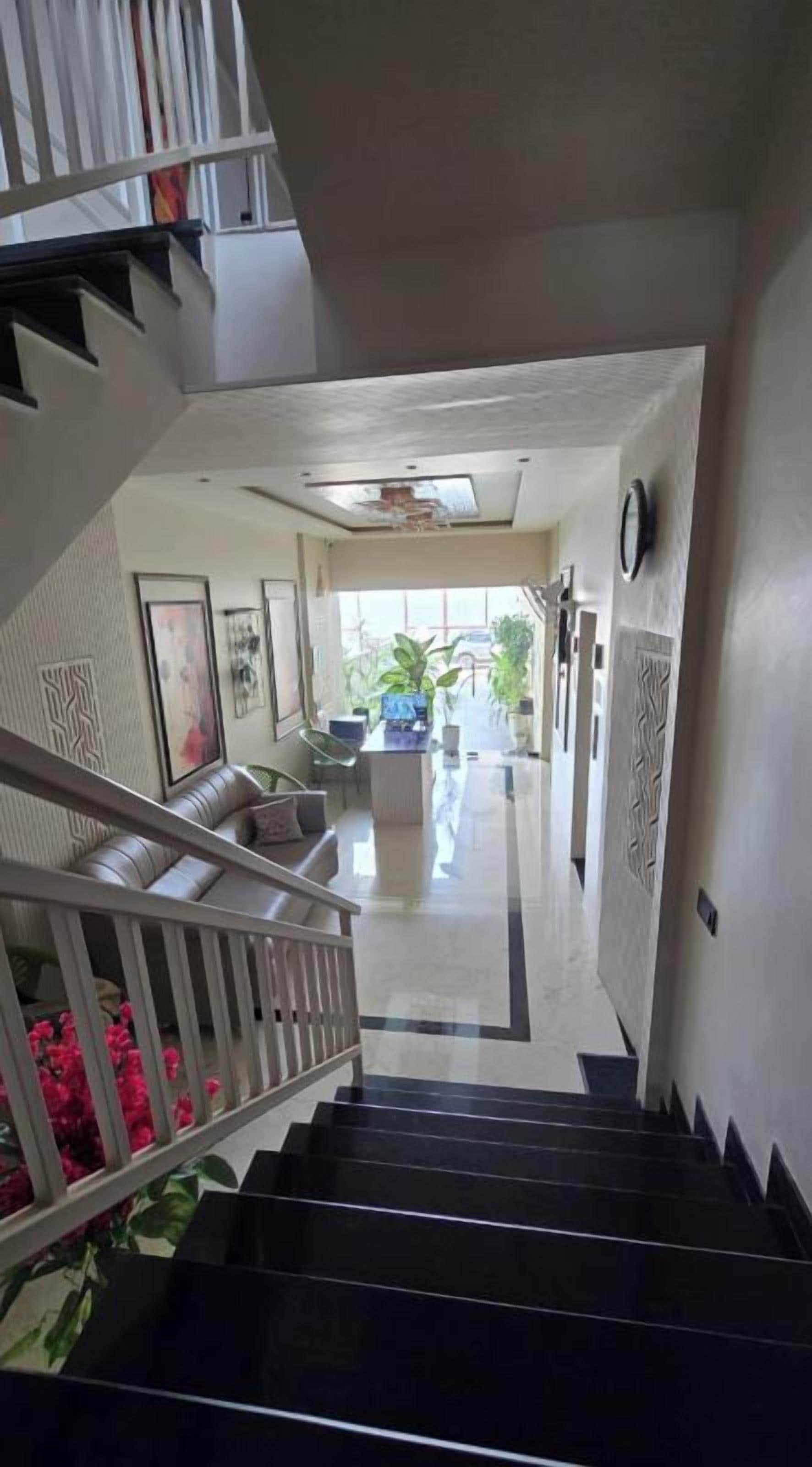 A staircase leading to a second-floor area with a view of a balcony and outdoor plants.