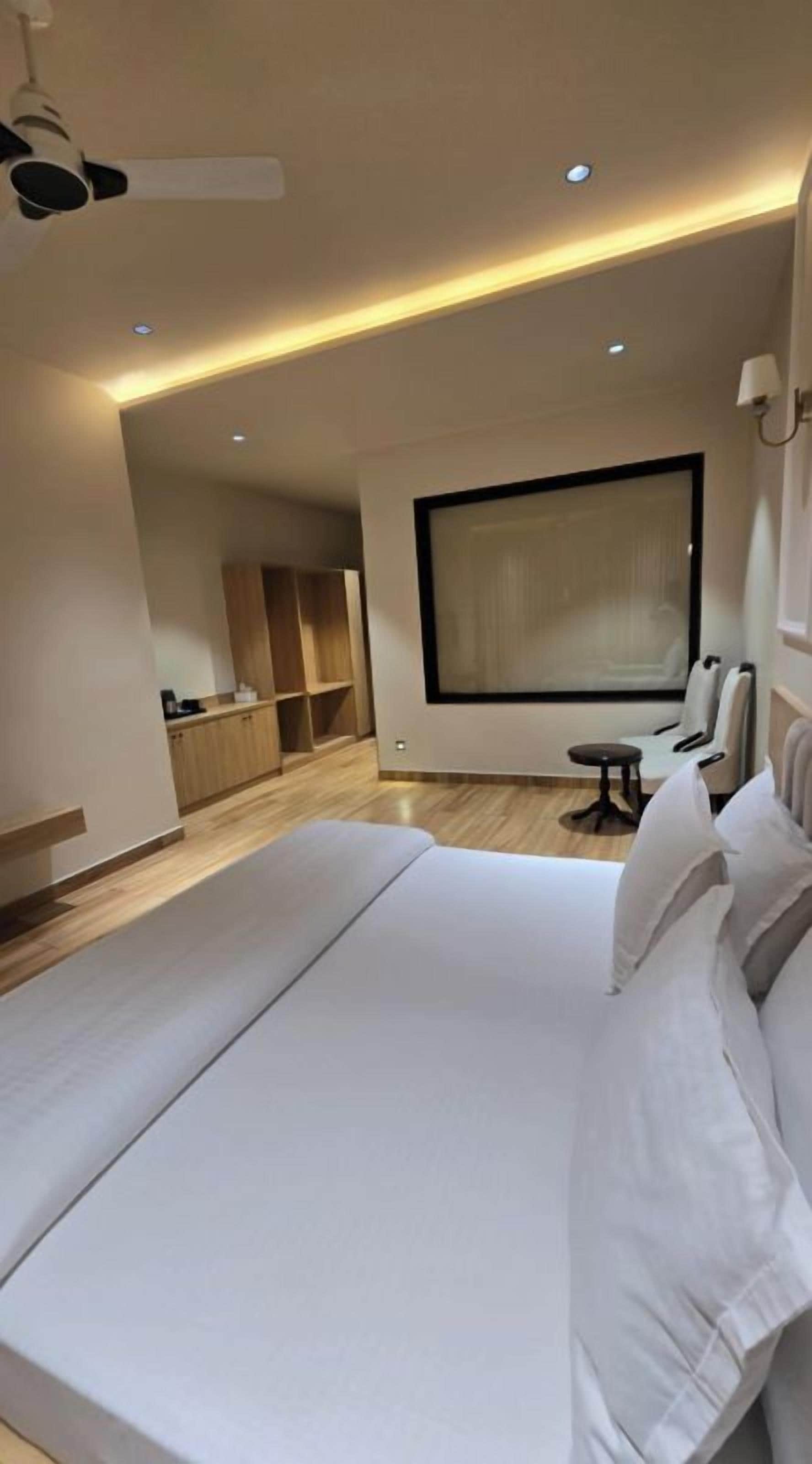 A modern hotel room with a large bed, a seating area, and a view of the city.