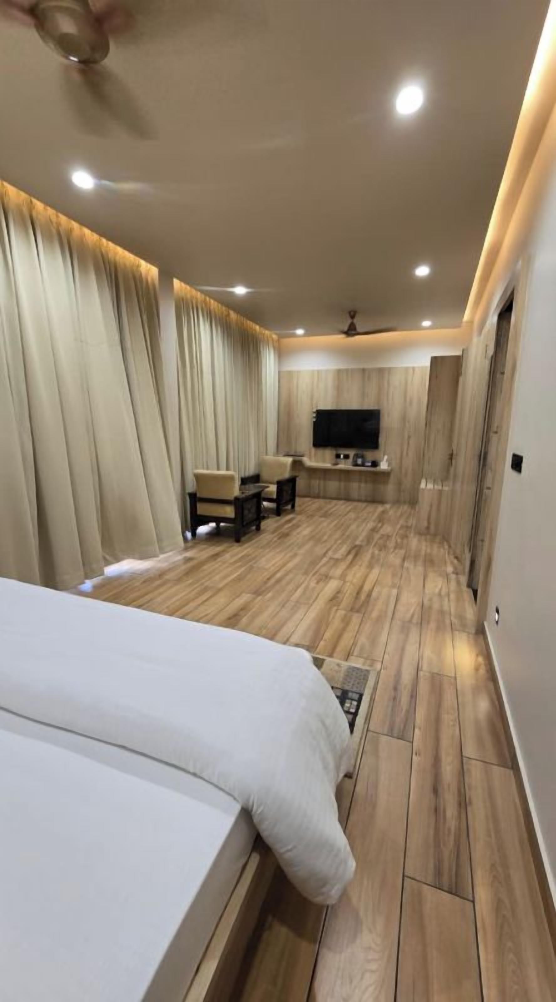 A hotel room with a bed, a seating area with chairs, a television, and a ceiling fan.