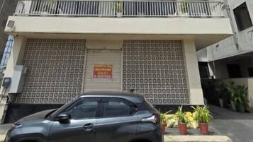 Un edificio de varios pisos con un coche estacionado adelante.