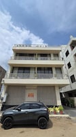 Un edificio de varios pisos con un coche estacionado adelante.