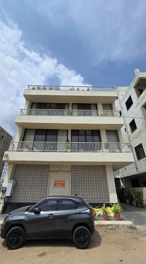 Un edificio de varios pisos con un coche estacionado adelante.