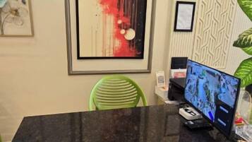 Un mostrador de recepción con un monitor de computadora, obras de arte enmarcadas y una silla verde.