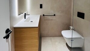 A modern bathroom with a wooden vanity, a white sink, a glass shower enclosure, and a toilet. - Fahana Residences Arguineguín (Arguineguín)