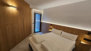 A modern bedroom with a large bed, wooden paneling, and built-in lighting. - Fahana Residences Arguineguín (Arguineguín)