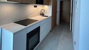 A modern kitchen with a built-in oven, a black faucet, and a marble countertop. - Fahana Residences Arguineguín (Arguineguín)