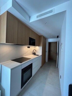 A modern kitchen with a built-in oven, a black faucet, and a marble countertop. - Fahana Residences Arguineguín (Arguineguín)