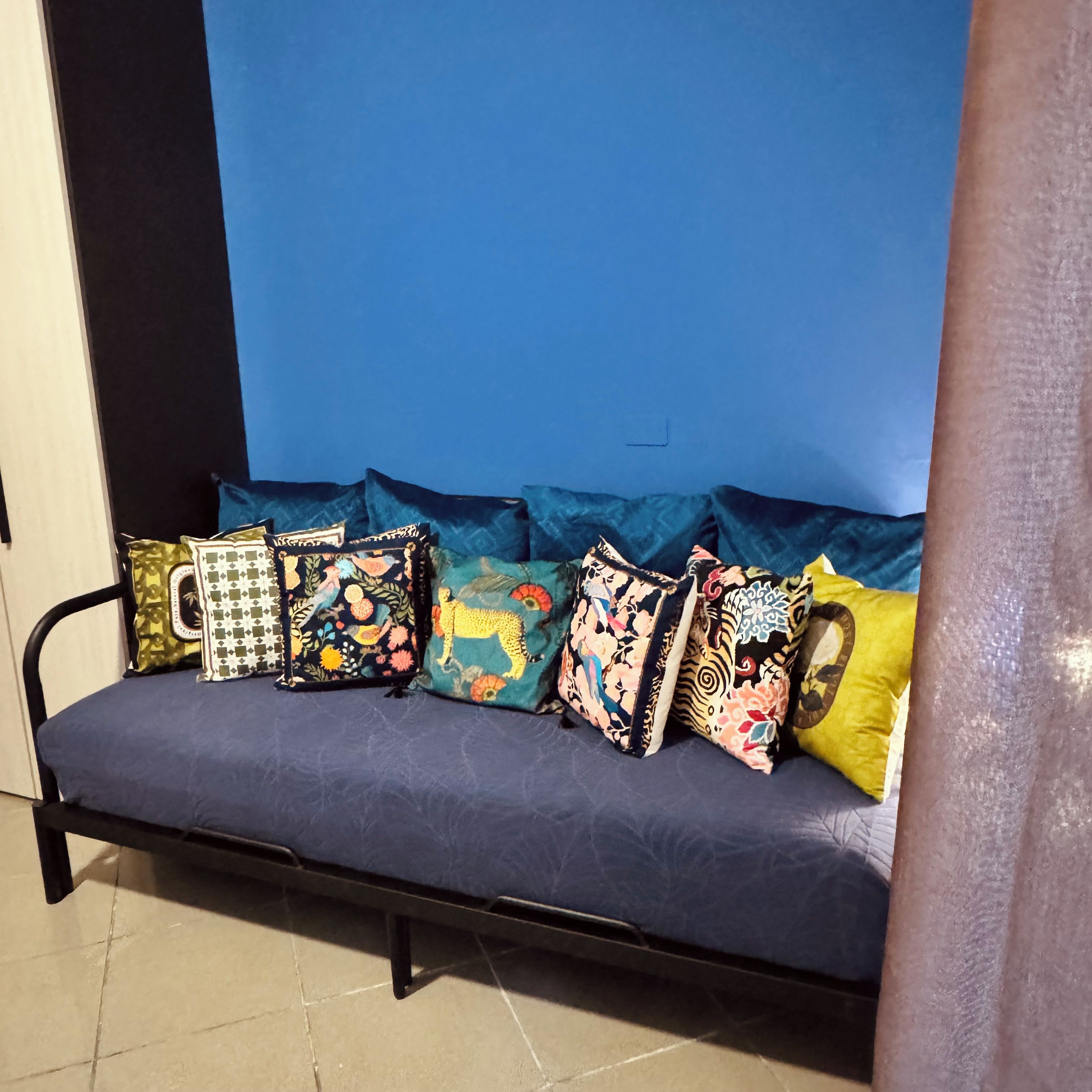 Ein Sofa mit bunten Kissen vor einer blauen Wand.