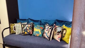 Ein Sofa mit bunten Kissen vor einer blauen Wand.