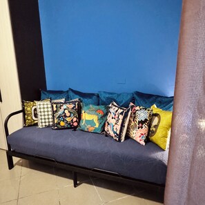 Ein Sofa mit bunten Kissen vor einer blauen Wand.