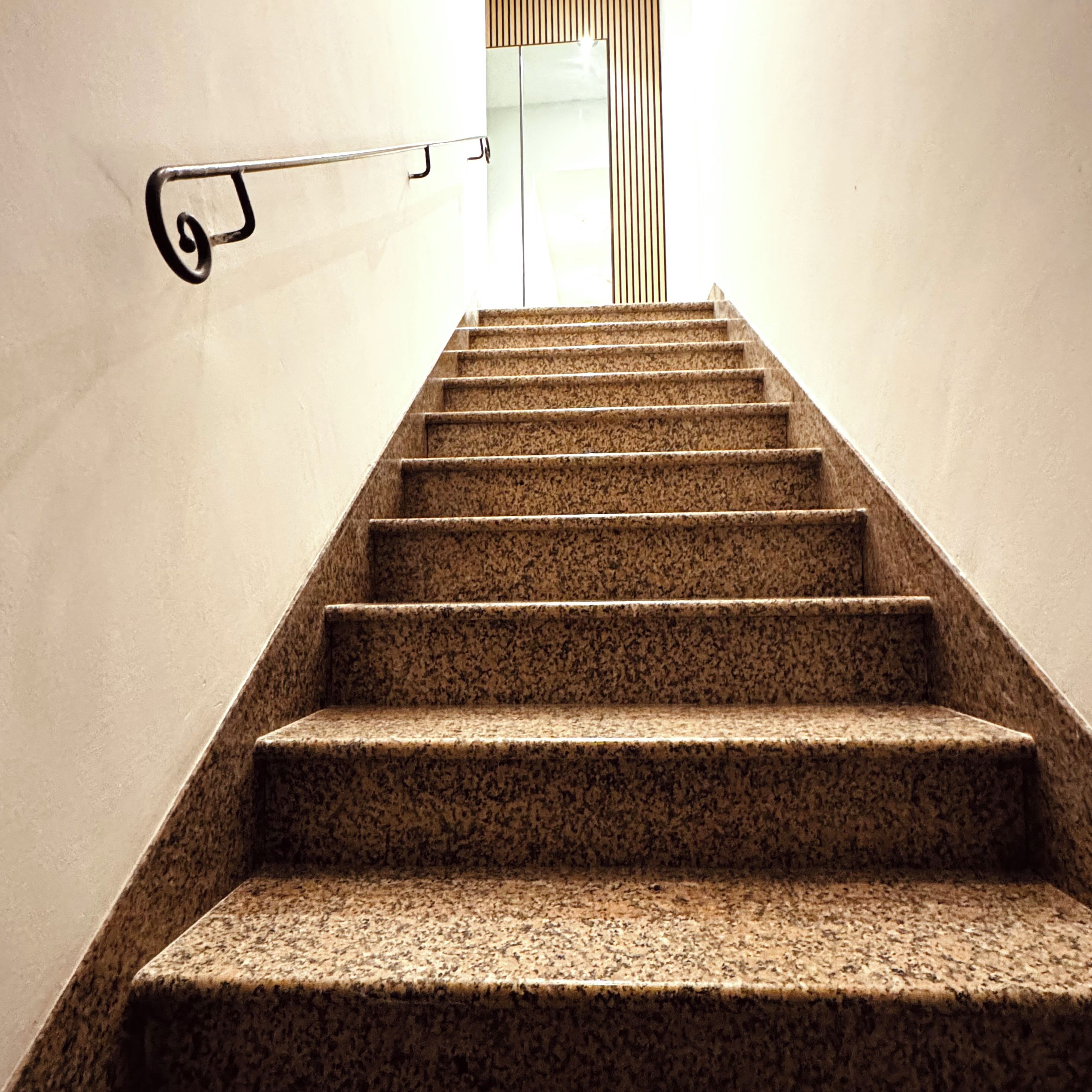 A staircase with a handrail and a wall-mounted light fixture.