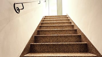 A staircase with a handrail and a wall-mounted light fixture.