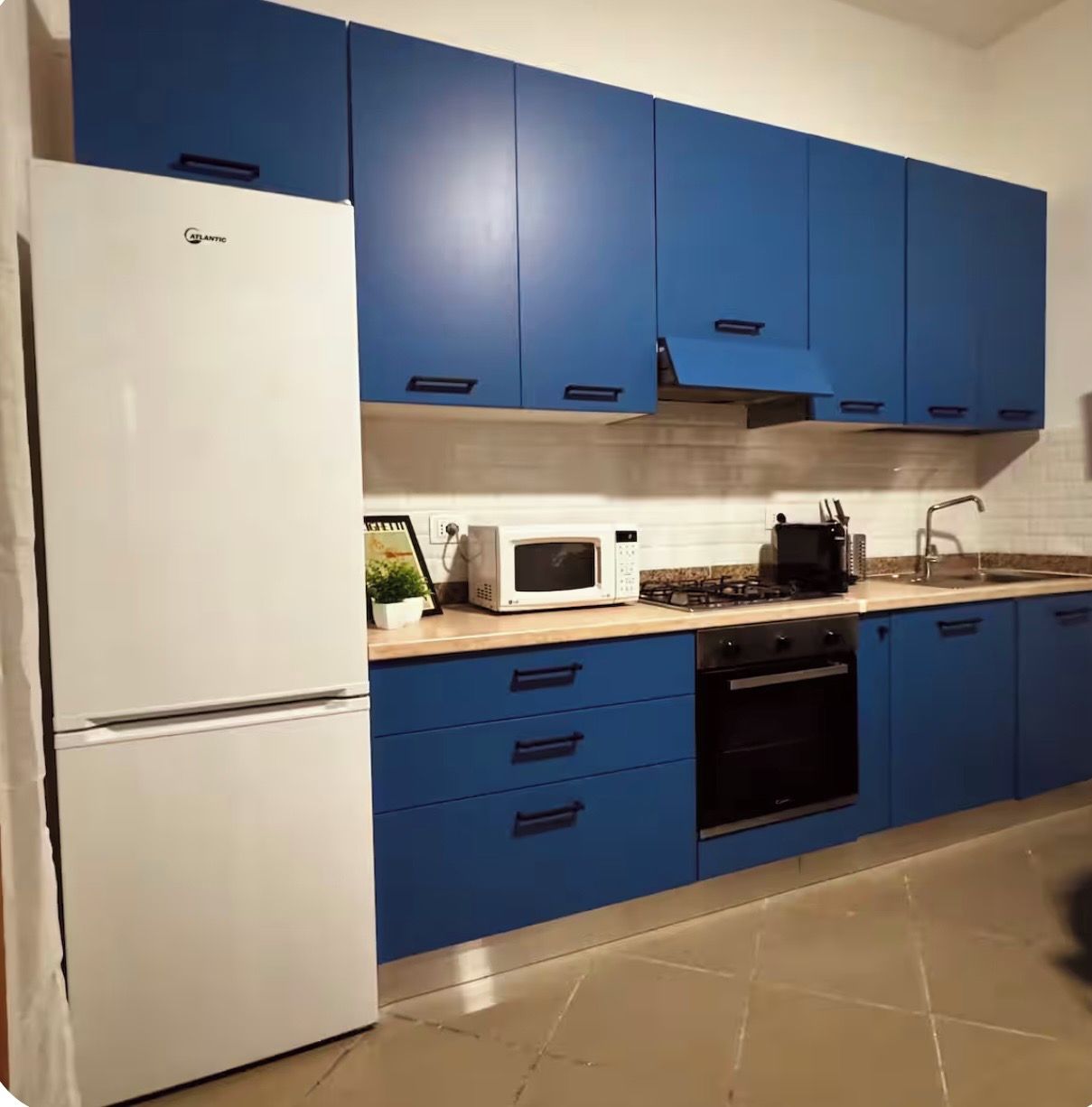 Eine Küche mit blauen Schränken, einem weißen Kühlschrank, einer Mikrowelle und einem Herd.