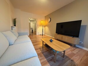 A living room with a sofa, a coffee table, a TV, and a lamp.
