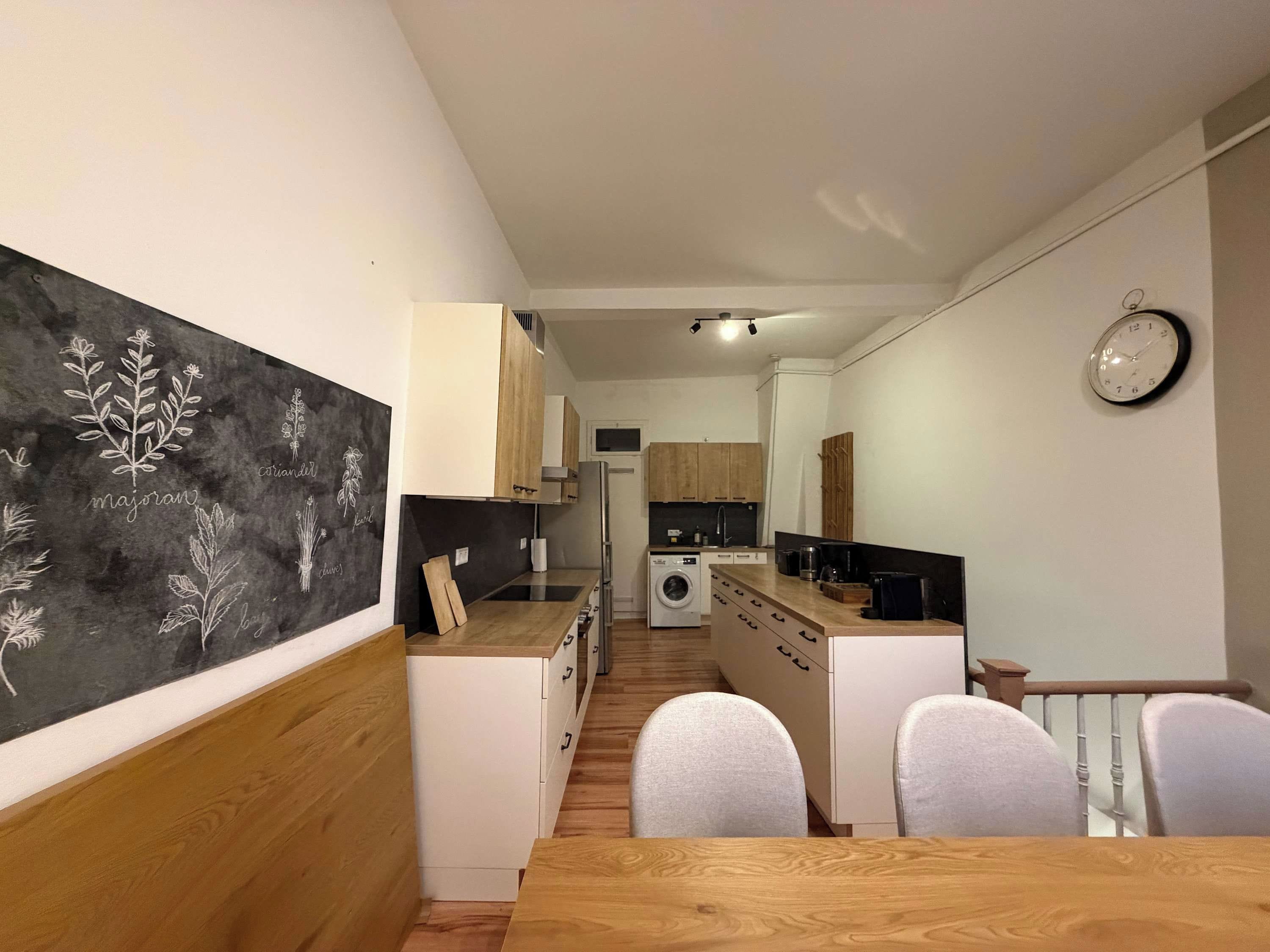 Eine moderne Küche mit Holzausstattung, einer eingebauten Waschmaschine und einem Essbereich mit Holztisch und -stühlen.