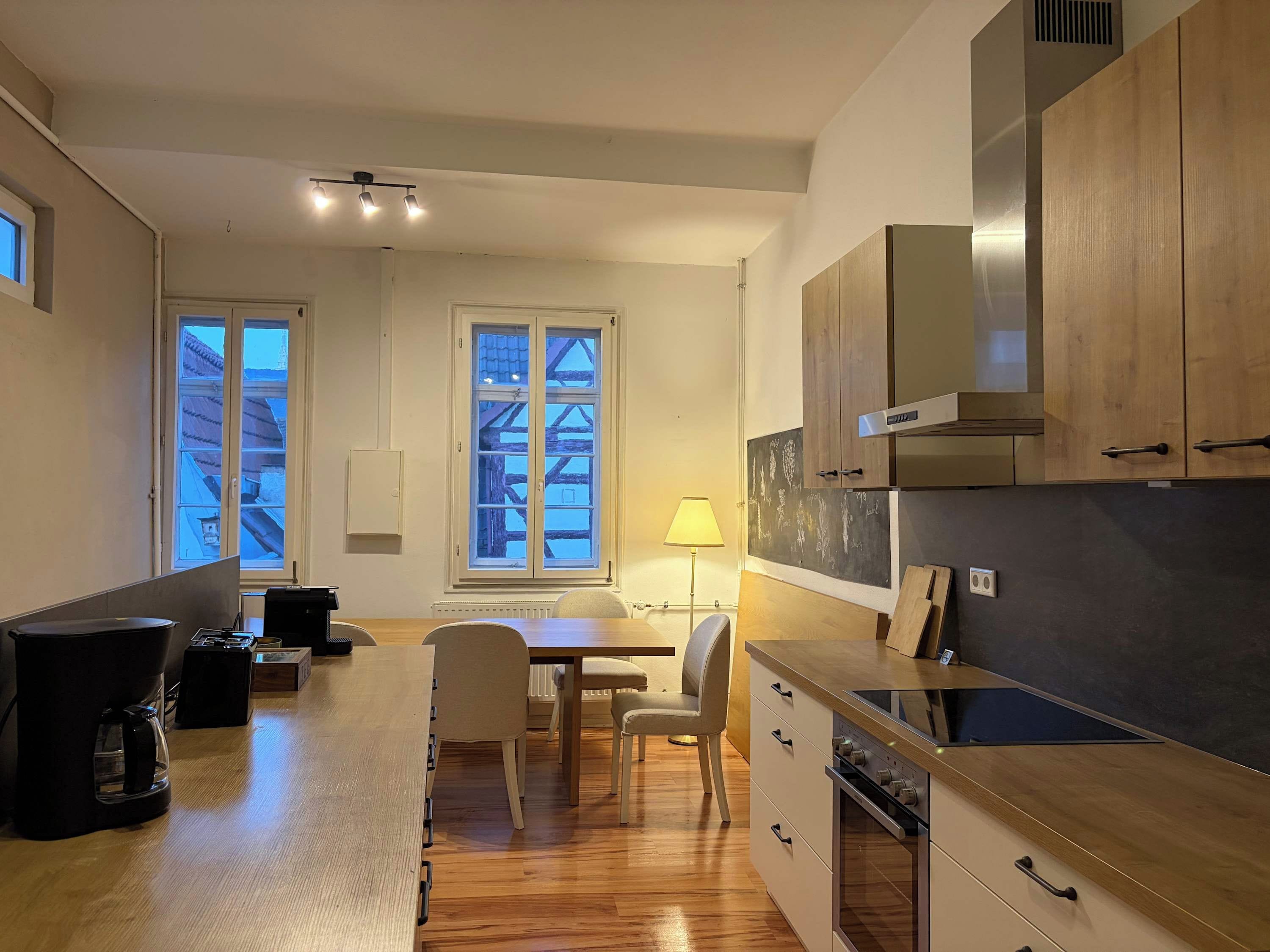 Une cuisine moderne avec des meubles en bois, un four encastré et un coin repas comprenant une table et des chaises.