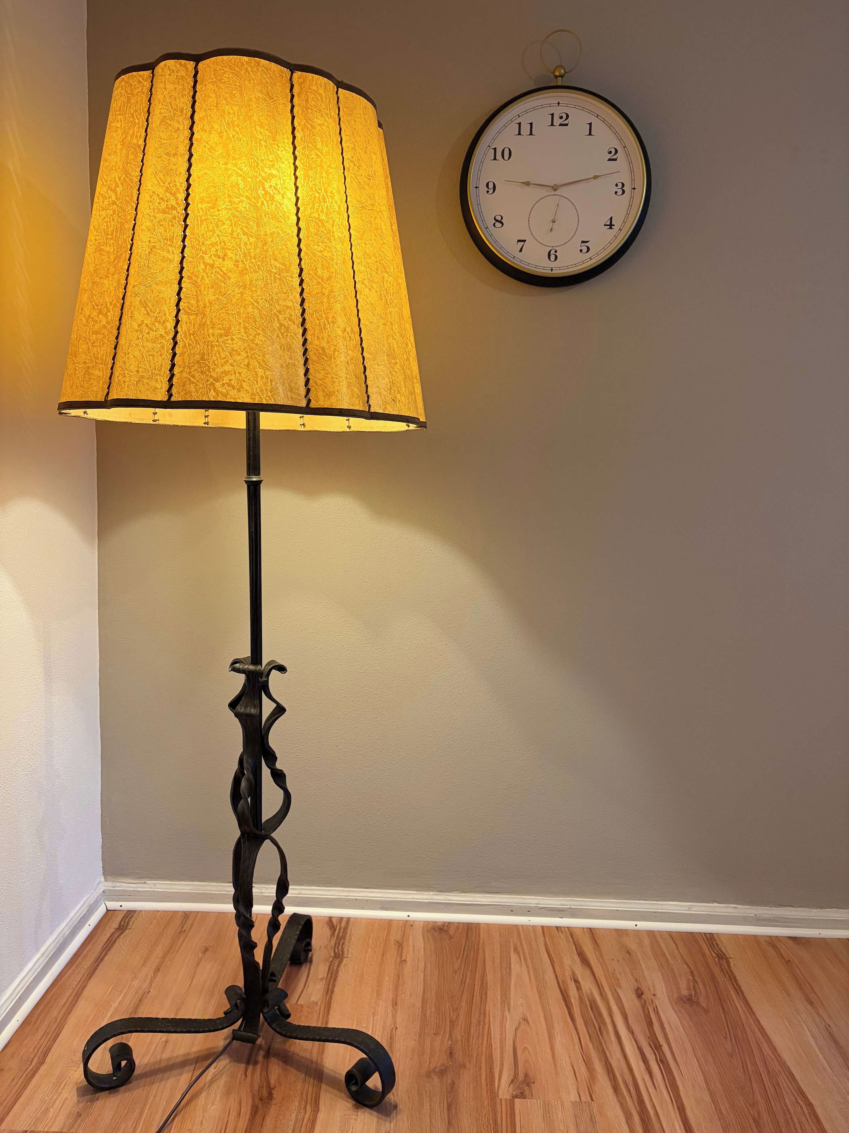 Eine Stehlampe mit strukturierter Lampenschirm und einer Wanduhr.