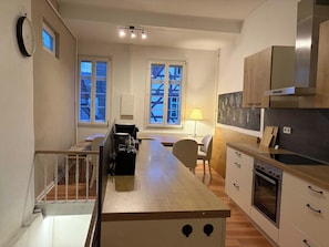 A modern kitchen with a central island, wooden cabinets, and a built-in oven.