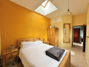 Ein Schlafzimmer mit Oberlicht, Holzmöbeln und Blick auf den Flur.