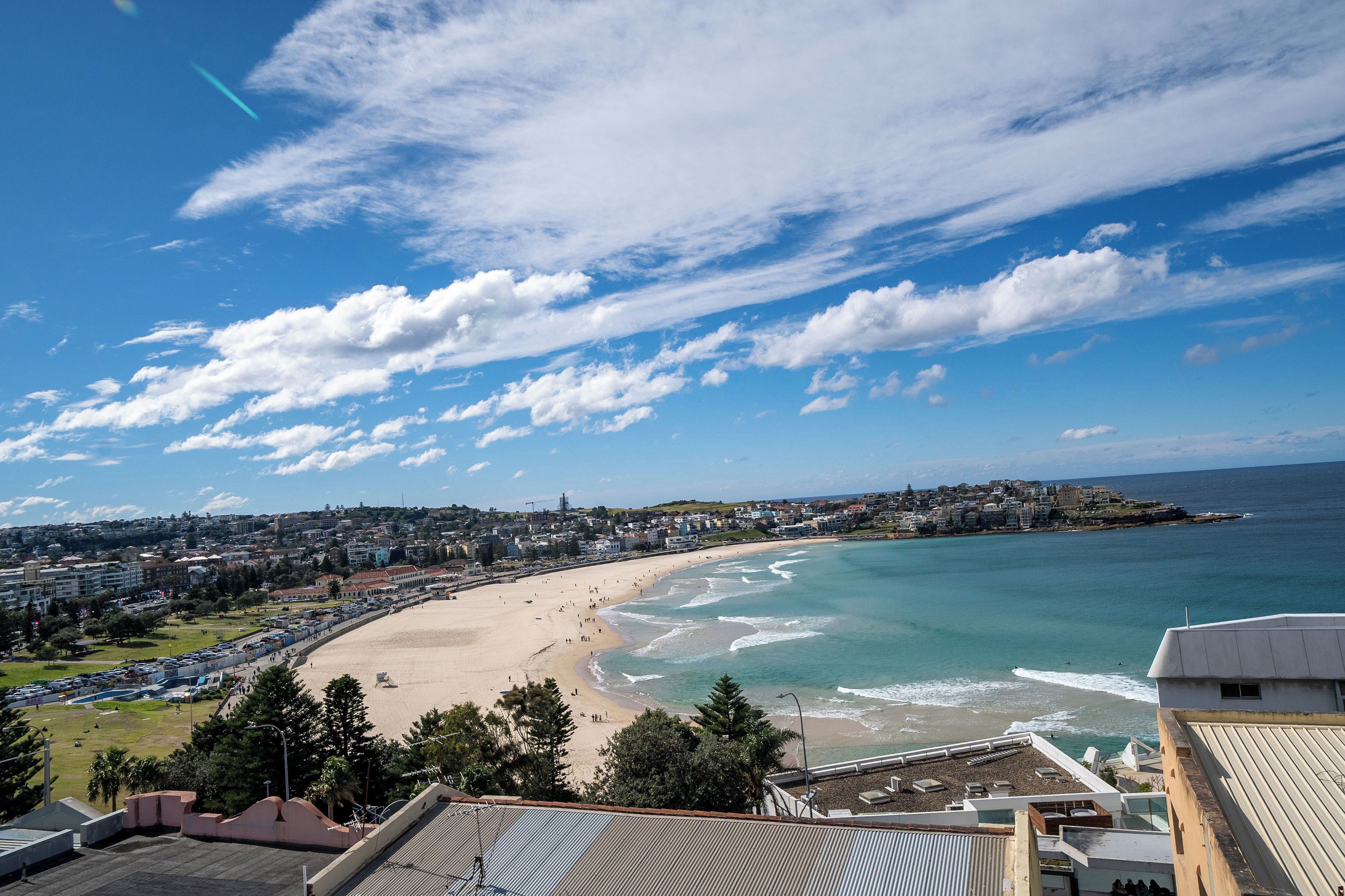 Paisagem costeira com praia, edifícios e céu claro.