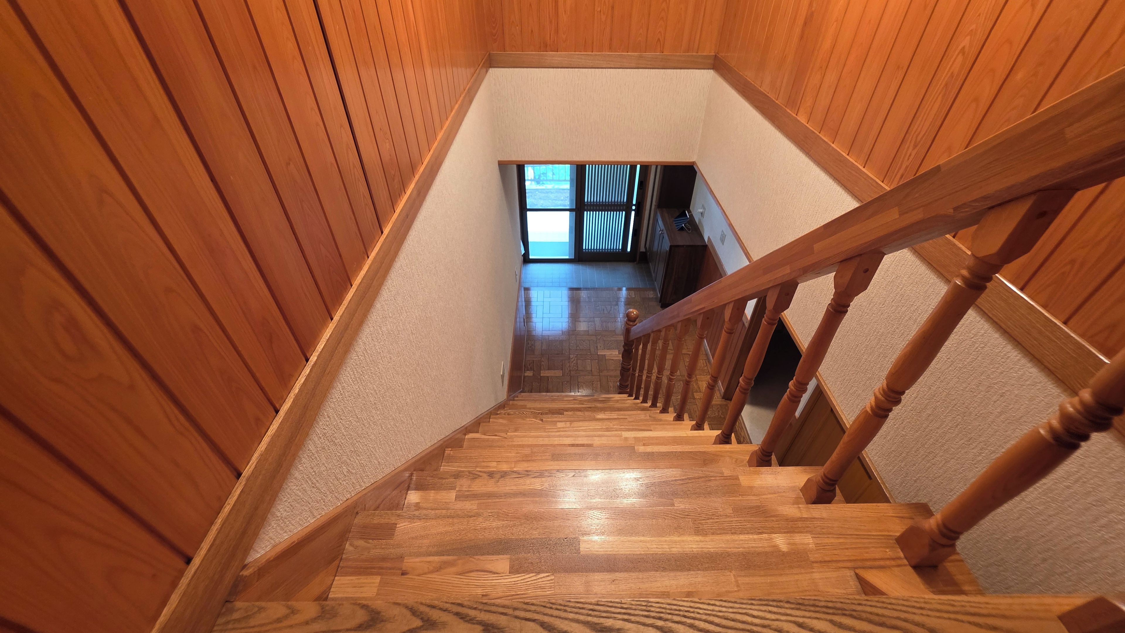 Un escalier en bois avec un palier recouvert de moquette et donnant sur une pièce avec une fenêtre.