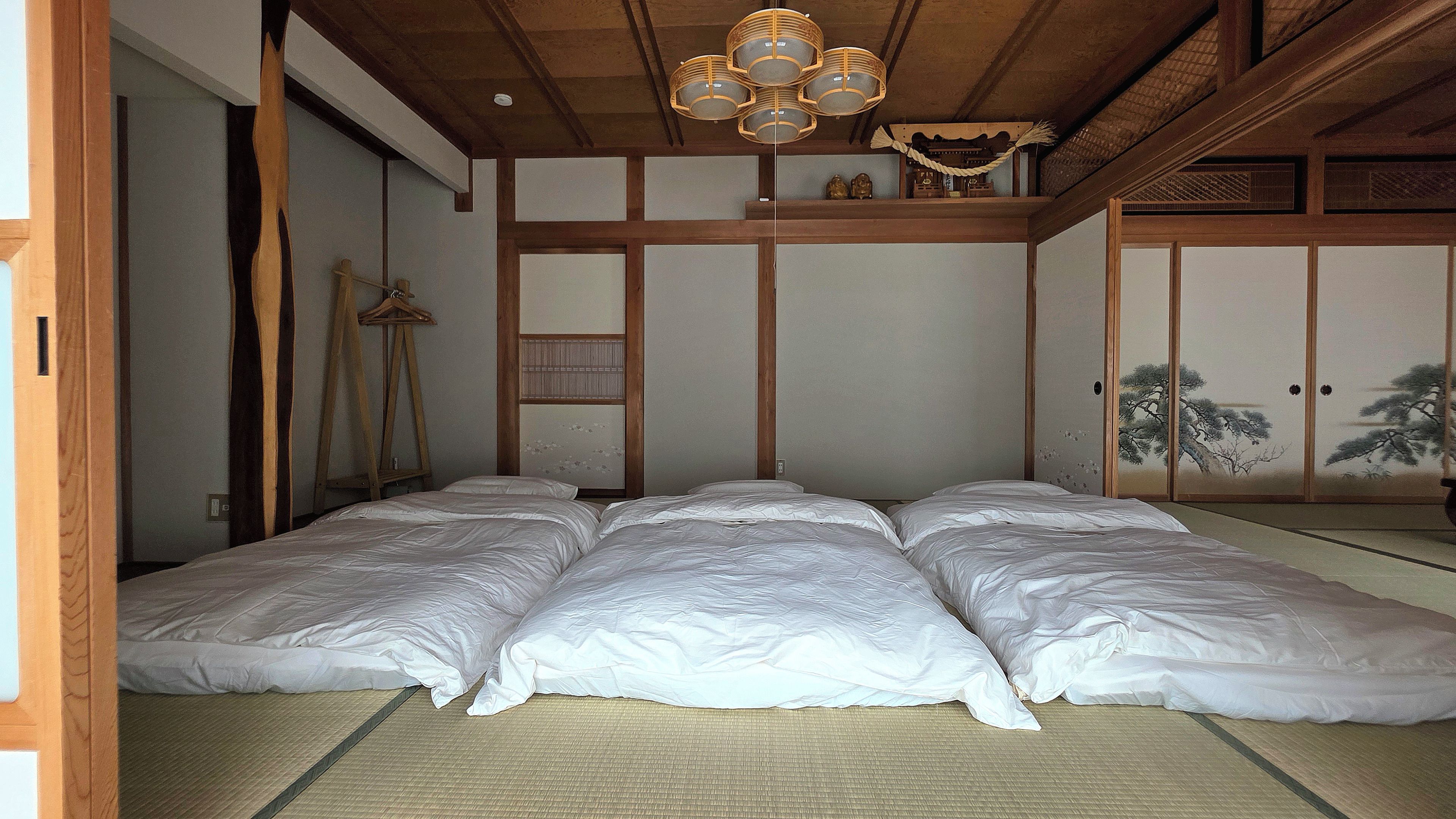 A traditional Japanese room with tatami flooring, a futon bed, a shoji screen, and a hanging lantern.
