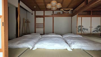A traditional Japanese room with tatami flooring, a futon bed, a shoji screen, and a hanging lantern.