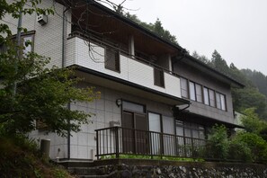 Un edificio de dos pisos con balcón y base de piedra.