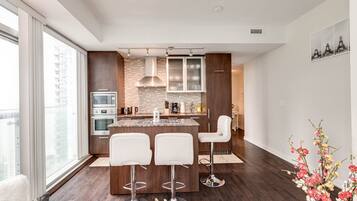A modern kitchen with a central island, bar stools, and a view of the city.